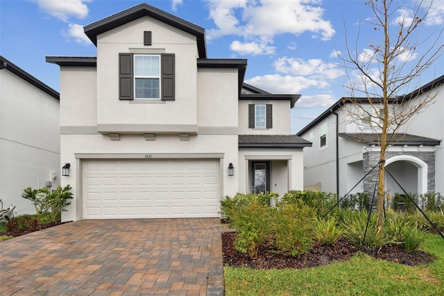 view of front of home with an attached garage, decorative driveway, and stucco siding