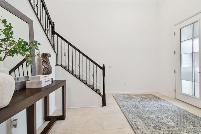 foyer with tile patterned flooring, a high ceiling, baseboards, and stairs