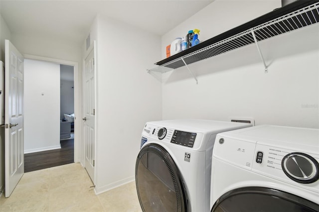 washroom featuring washing machine and dryer, laundry area, visible vents, and baseboards