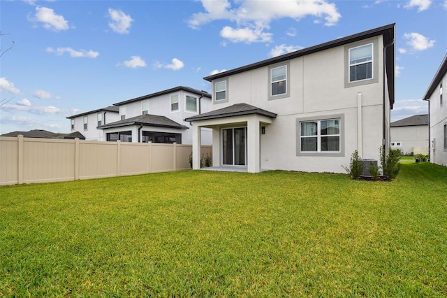 back of property with fence, a lawn, and stucco siding