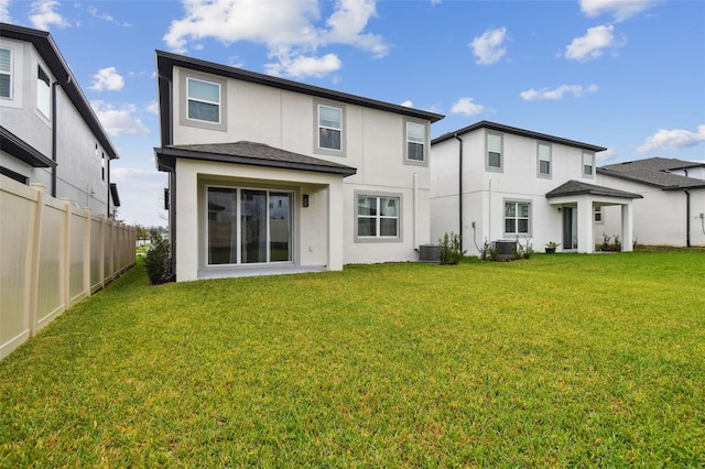 rear view of property featuring central AC unit, stucco siding, fence, and a yard