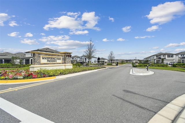 view of road featuring a residential view, curbs, and a gated entry