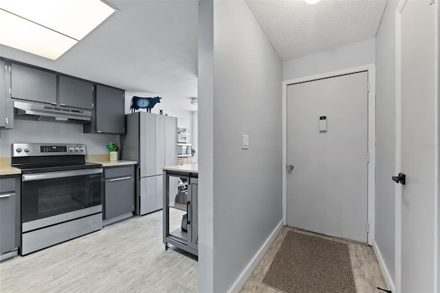 kitchen with stainless steel appliances, light hardwood / wood-style floors, and a textured ceiling