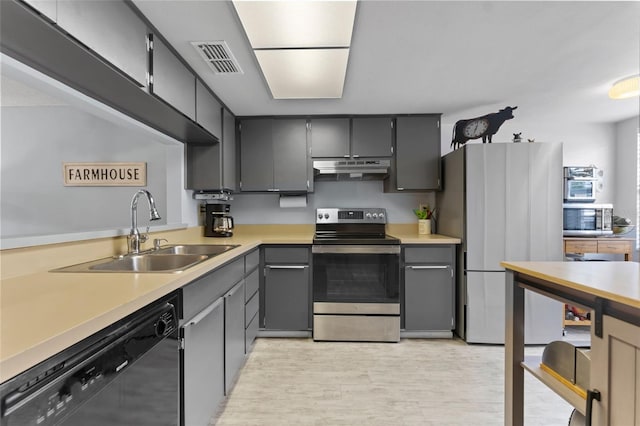 kitchen with stainless steel appliances, sink, gray cabinetry, and light wood-type flooring