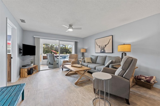 living room featuring a textured ceiling, light hardwood / wood-style flooring, and ceiling fan