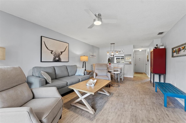 living room with a textured ceiling, wood-type flooring, and ceiling fan