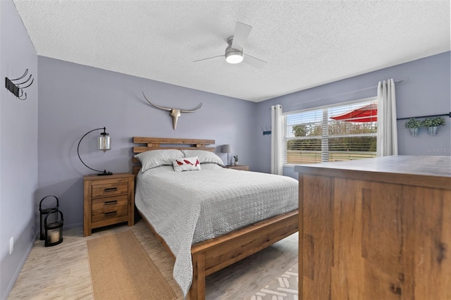 bedroom with ceiling fan, a textured ceiling, and light hardwood / wood-style flooring