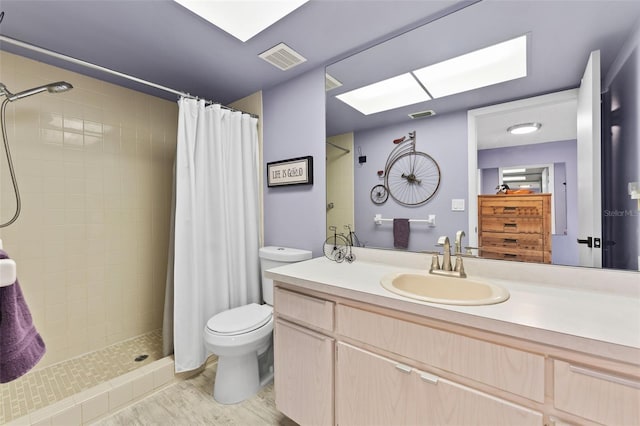 bathroom featuring a skylight, wood-type flooring, vanity, toilet, and a shower with curtain