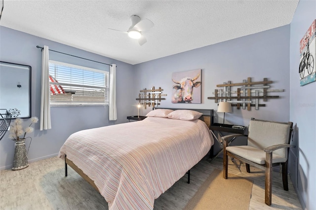 bedroom featuring ceiling fan, light hardwood / wood-style flooring, and a textured ceiling