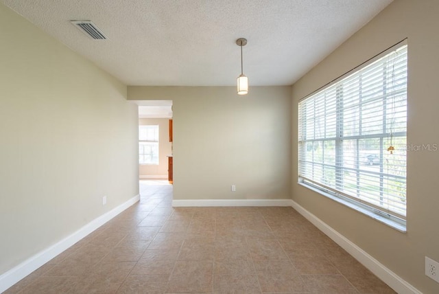 spare room featuring a textured ceiling and light tile patterned floors