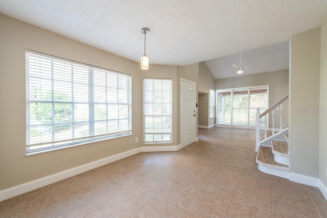 unfurnished room featuring lofted ceiling, light tile patterned floors, and a textured ceiling