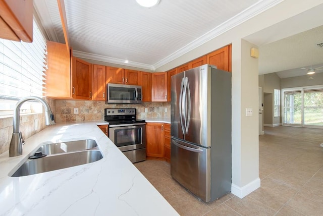 kitchen featuring appliances with stainless steel finishes, sink, decorative backsplash, ornamental molding, and light stone counters