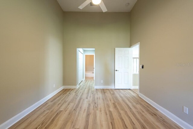 spare room featuring a high ceiling, ceiling fan, and light hardwood / wood-style floors