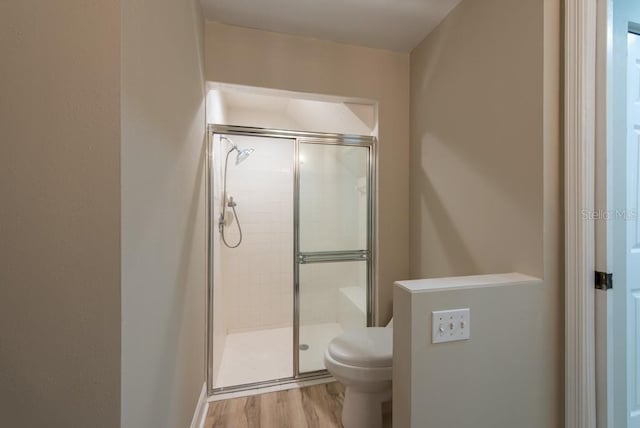 bathroom featuring wood-type flooring, toilet, and an enclosed shower