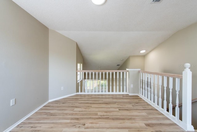 interior space with lofted ceiling, light hardwood / wood-style flooring, and a textured ceiling