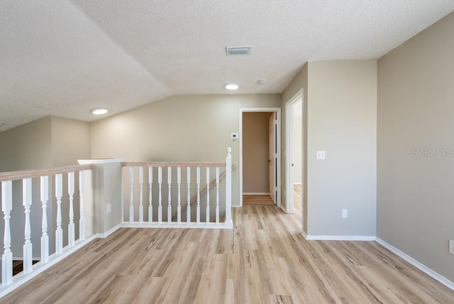 interior space featuring vaulted ceiling, a textured ceiling, and light wood-type flooring