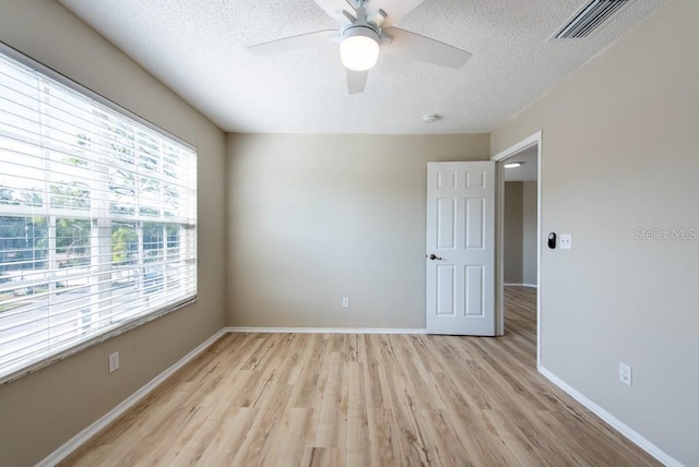 empty room featuring ceiling fan, light hardwood / wood-style floors, and a textured ceiling