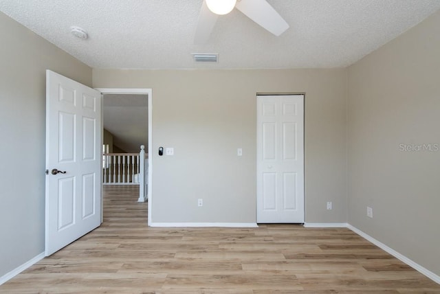 unfurnished bedroom with ceiling fan, a closet, a textured ceiling, and light hardwood / wood-style flooring