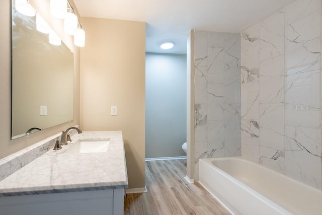 full bathroom with tiled shower / bath, vanity, toilet, and wood-type flooring