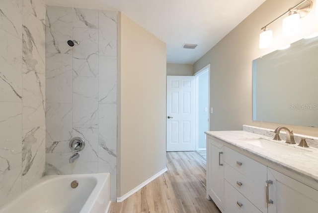 bathroom featuring vanity, wood-type flooring, and tiled shower / bath