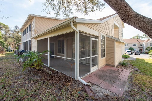 view of side of property featuring a patio, a sunroom, and cooling unit