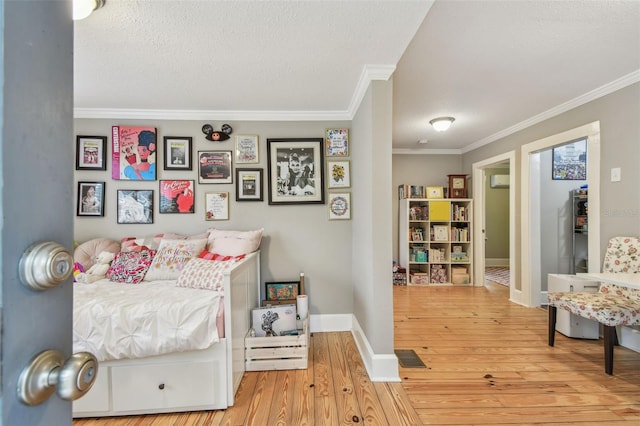 bedroom featuring ornamental molding, a textured ceiling, and light hardwood / wood-style flooring