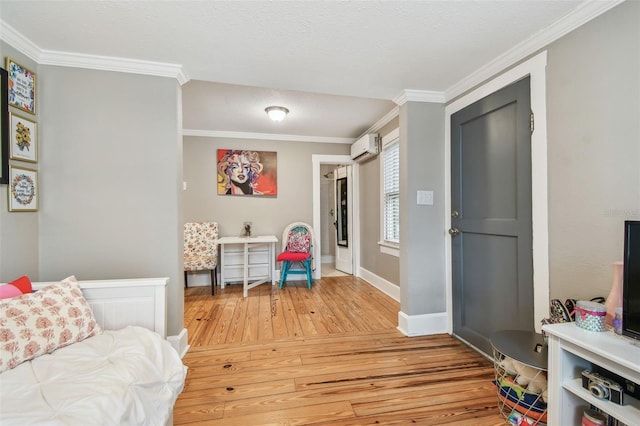 interior space with ornamental molding, wood-type flooring, a wall unit AC, and a textured ceiling