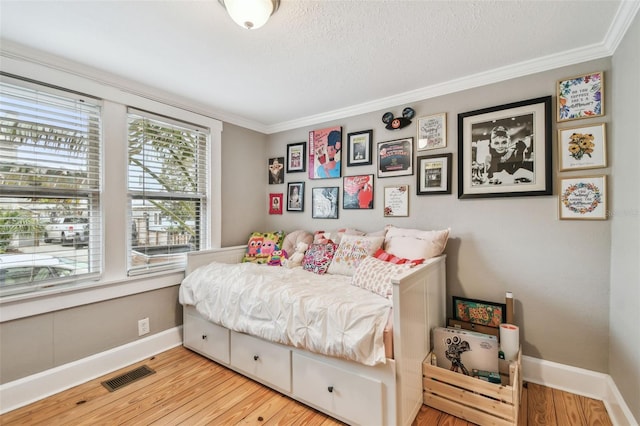 bedroom with crown molding, a textured ceiling, and light wood-type flooring