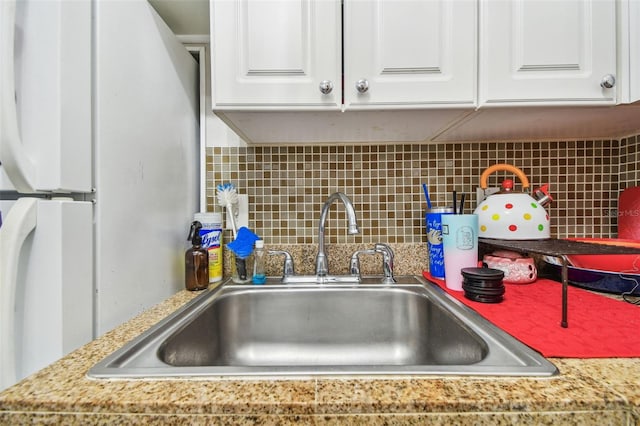 details featuring backsplash, sink, and white cabinets