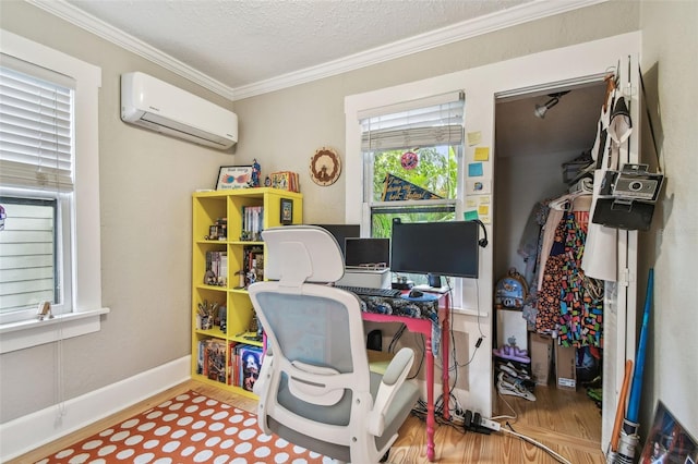 office space featuring hardwood / wood-style floors, ornamental molding, a wall unit AC, and a textured ceiling