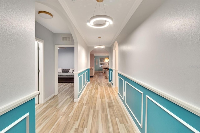 hall with crown molding and light hardwood / wood-style floors