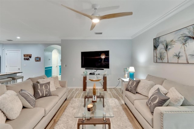 living room featuring ceiling fan, ornamental molding, and light wood-type flooring