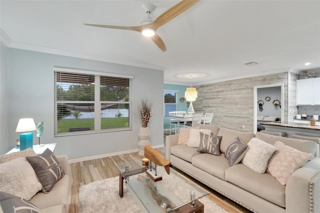 living room with crown molding, light hardwood / wood-style flooring, and ceiling fan