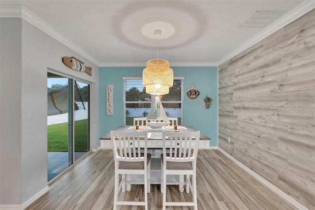 dining area with wooden walls, ornamental molding, and light wood-type flooring