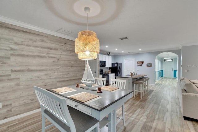 dining space with ornamental molding and light wood-type flooring