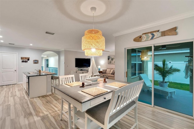 dining space with ornamental molding and light hardwood / wood-style floors