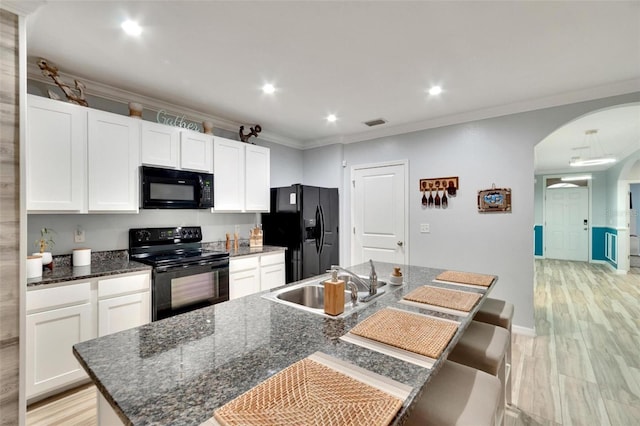 kitchen with white cabinets, sink, a kitchen island with sink, and black appliances