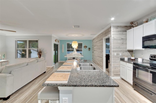 kitchen with white cabinetry, a kitchen island with sink, sink, and black appliances