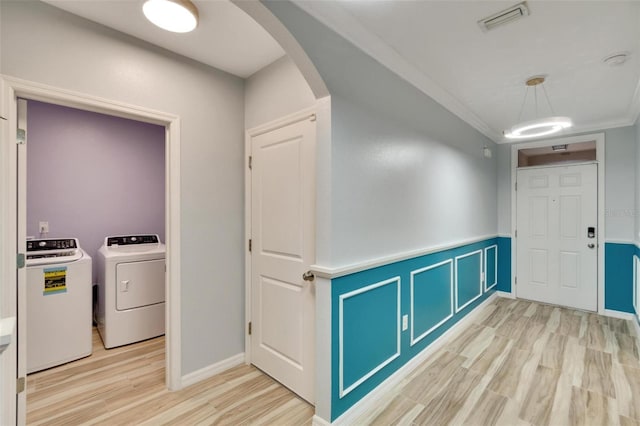 interior space with crown molding, light hardwood / wood-style flooring, and washing machine and dryer