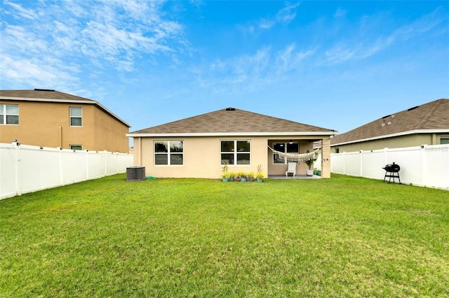 rear view of house featuring cooling unit and a yard