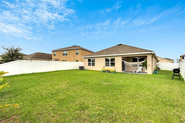 rear view of house with cooling unit, a yard, and a patio area