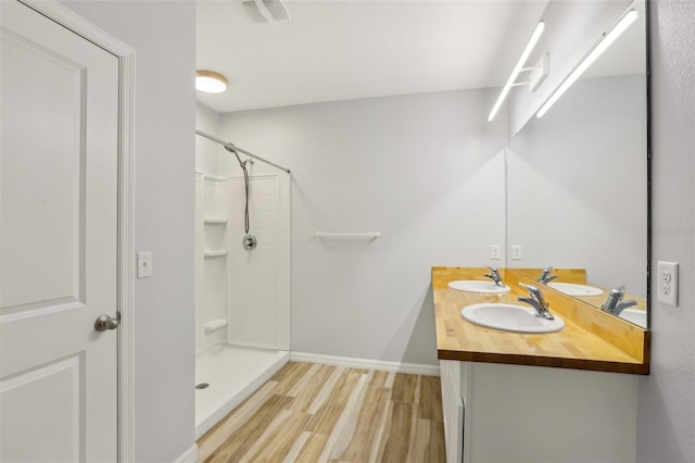 bathroom with wood finished floors, walk in shower, and a sink