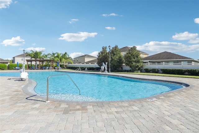 community pool with a patio area, a pergola, and fence