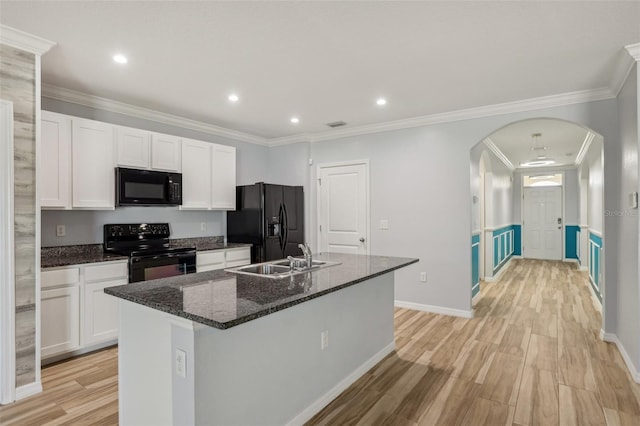 kitchen featuring a sink, black appliances, arched walkways, white cabinetry, and a kitchen island with sink