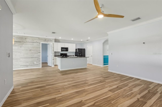 kitchen featuring black appliances, ornamental molding, open floor plan, arched walkways, and white cabinets