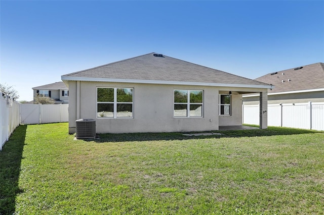 back of property with a yard, a fenced backyard, central AC, and stucco siding