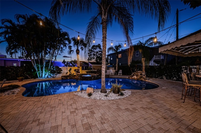 pool at dusk featuring a patio