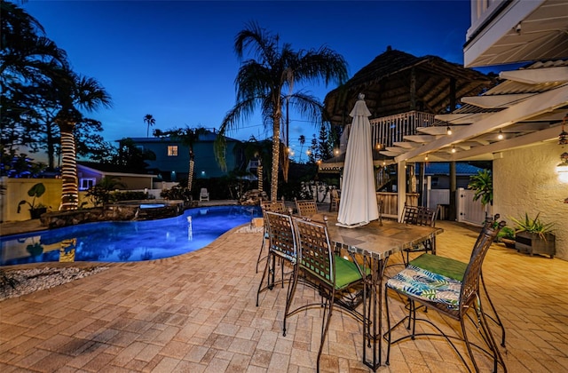 pool at dusk with an in ground hot tub, a pergola, an outdoor bar, and a patio area