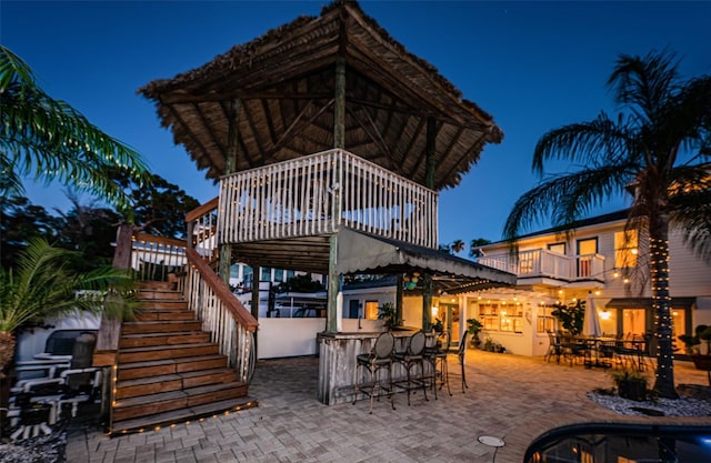 patio at night featuring a bar and a balcony