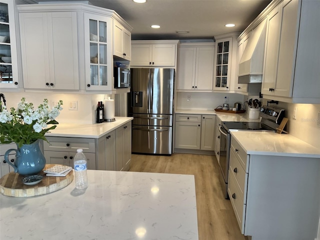 kitchen featuring white cabinetry, stainless steel appliances, and wall chimney exhaust hood